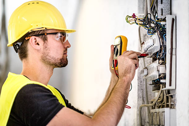 Electrician repairing circuit breakers in industrial electric panel.