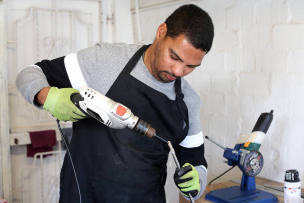 A Golf Club Builder uses a drill to clean out the inside of a golf club shaft while making a repair